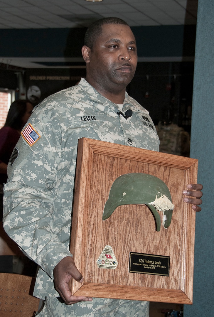 Army Staff Sgt. Thalamus Lewis poses for a photo with a portion of the Advanced Combat Helmet that saved his life on Oct. 4, 2012, when a bullet slammed into his helmet and knocked him out. The helmet is one example of the many types of protective equipment DLA Troop Support buys for soldiers.