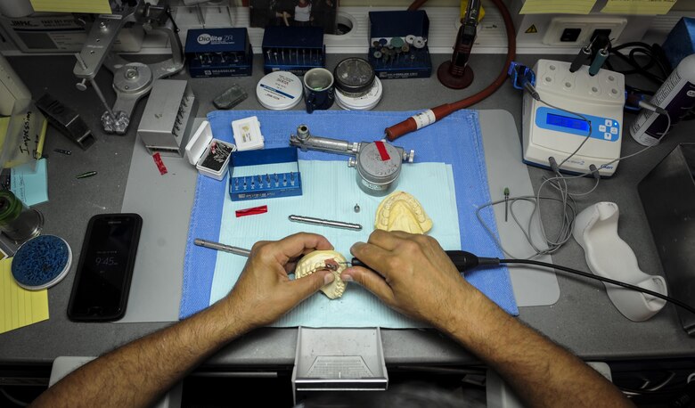 Edward Ibarra, a dental laboratory technician with the 1st Special Operations Dental Squadron, refines an implant at Hurlburt Field, Fla., April 18, 2016. The dental laboratory creates mouth appliances for patients prescribed by the dentists. Appliances may be permanent or removable depending on the treatment plan. (U.S. Air Force photo by Senior Airman Meagan Schutter)