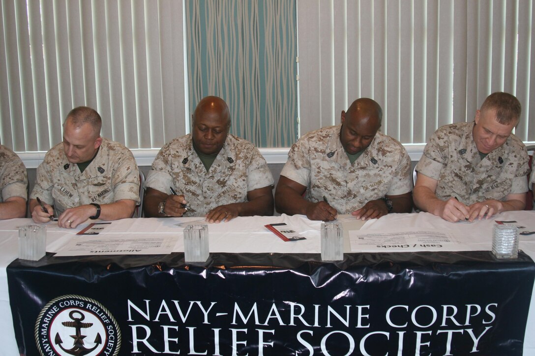 Sgt. Maj. Justin LeHew, Training and Education Command; Master Gunnery Sgt. Andre Mayhue, Transportation Branch chief; Sgt. Maj. Gerald Saunders, Marine Corps Base Quantico; and Sgt. Maj. Thomas Johnson, Headquarters and Service Battalion, sign pledge forms to the Navy Marine Corps Relief Society at a Professional Military Education Session held Apr. 13 at The Clubs at Quantico.