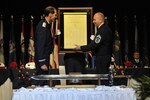 Chief Master Sgt. James W. Hotaling, the command chief master sergeant of the Air National Guard, presents Lt. Gen. Stanley E. Clarke III, director of the Air National Guard, with a scroll signed by the enlisted Airmen attending his Order of the Sword induction ceremony at the Renaissance hotel Montgomery, Alabama, April 17, 2016. Clarke is the 13th Air National Guard officer to be inducted into the Order of the Sword, which is the top honor the enlisted corps can bestow upon an officer. 