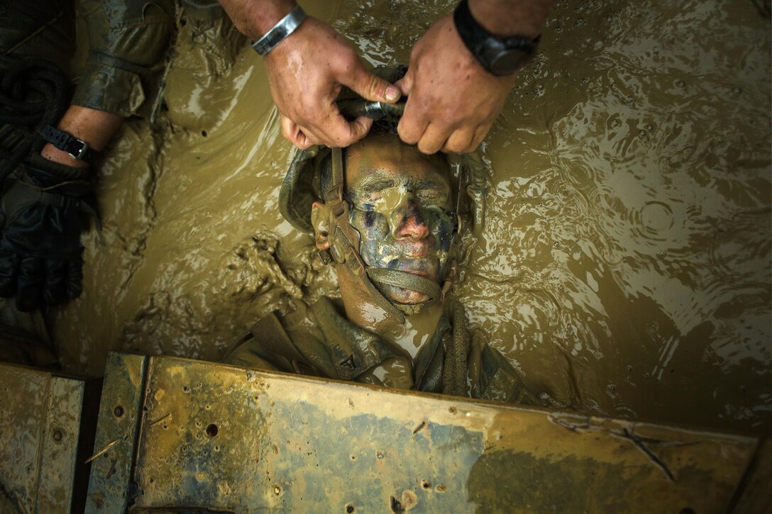 Combat Training: A Marine purses his lips and squeezing his eyes shut as he is dragged from a mock booby trap in the “Pit and Pond” obstacle during the endurance course at the Jungle Warfare Training Center, Okinawa, Japan, April 19, 2015. The endurance course is the final event Marines participating in jungle warfare training must face, trudging through roughly five miles of Okinawa jungle through 30 obstacles. Marines got creative in shuffling their squad mates beneath loose Plexiglas, avoiding contact with the “booby trap” at all costs. If any portion of the pane is touched, all Marines in a five-meter radius are considered casualties and have to go back through the Pit and Pond. The Marines are with Company L, 3rd Battalion, 3rd Marine Regiment. The Hawaii-based battalion is attached to 4th Marine Regiment, 3rd Marine Division, III Marine Expeditionary Force as part of the unit deployment program. U.S. Marine Corps photo by Sgt. Matthew Callahan