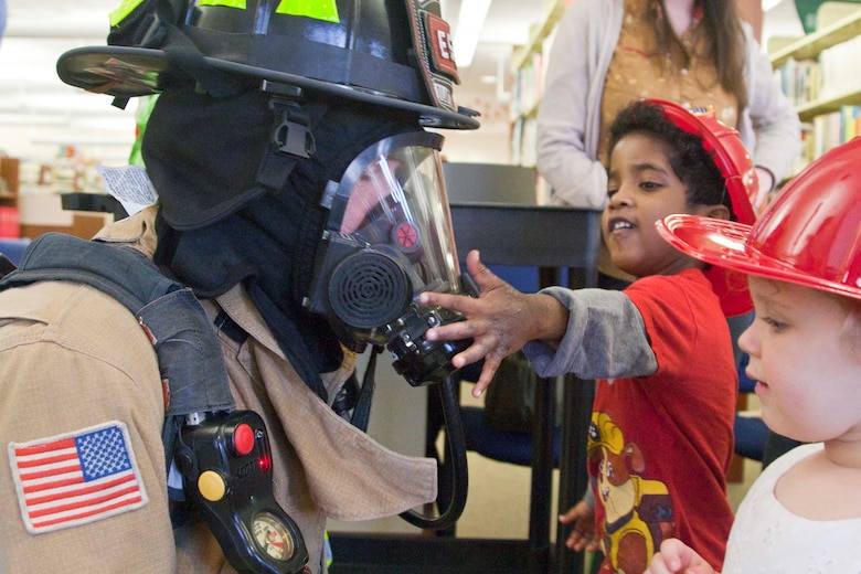 Preston, 7, is adorned with a toy firefighter hat from a local first responder in Quantico Fire Station 531.