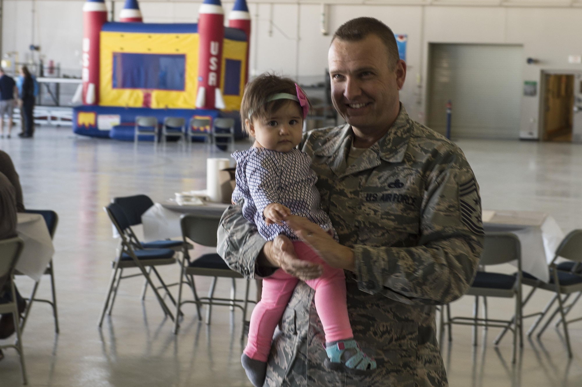 Chief Master Sgt. Michael Ditore, 432nd Wing/432nd Air Expeditionary Wing command chief, watch A tribute band to The Bee Gees with his daughter at the April 16, 2016, at Creech Air Force Base, Nevada.  This event was held to help boost morale of Creech members and their families, which included games, food, and musical performances. (U.S. Air Force photo by Senior Airman Adarius Petty/Released)