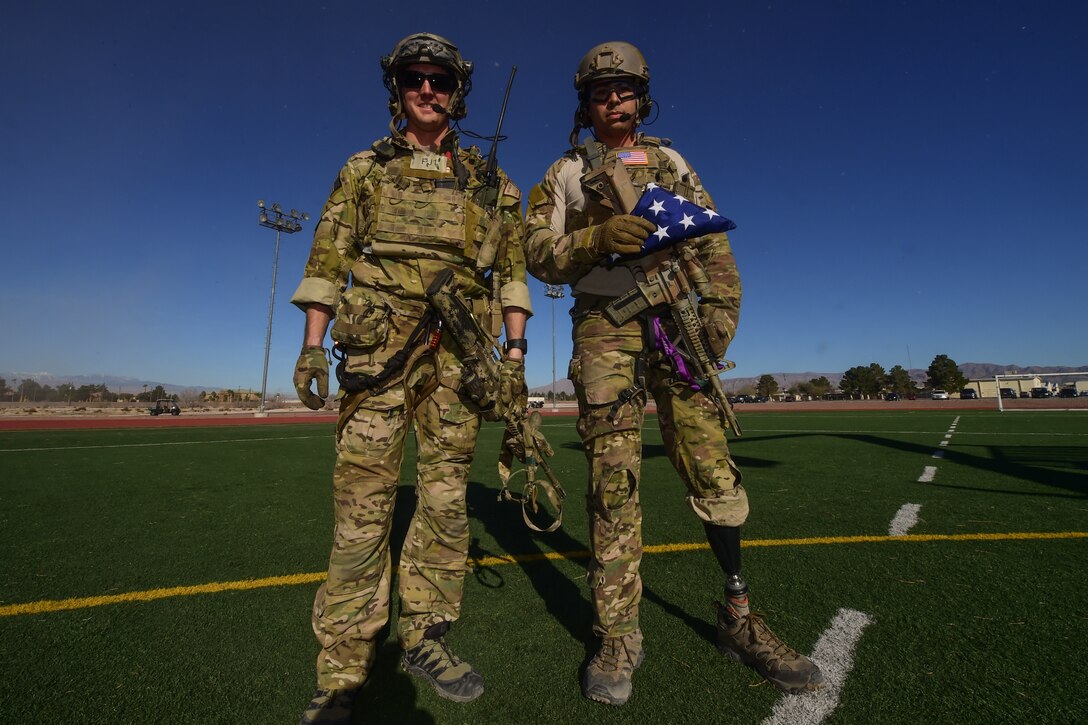 Wounded warriors and Air Force pararescuemen Staff Sgt. August O’Niell, right, and Staff Sgt. Nick Robillard pose for a portrait with the Air Force Wounded Warrior Program flag at the 2016 U.S. Air Force Trials at Nellis Air Force Base, Nev., Feb. 26, 2016. O’Niell is training to recertify for duty as a pararescueman after the loss of his leg due to wounds suffered in Afghanistan. Air Force photo by Senior Airman Taylor Curry