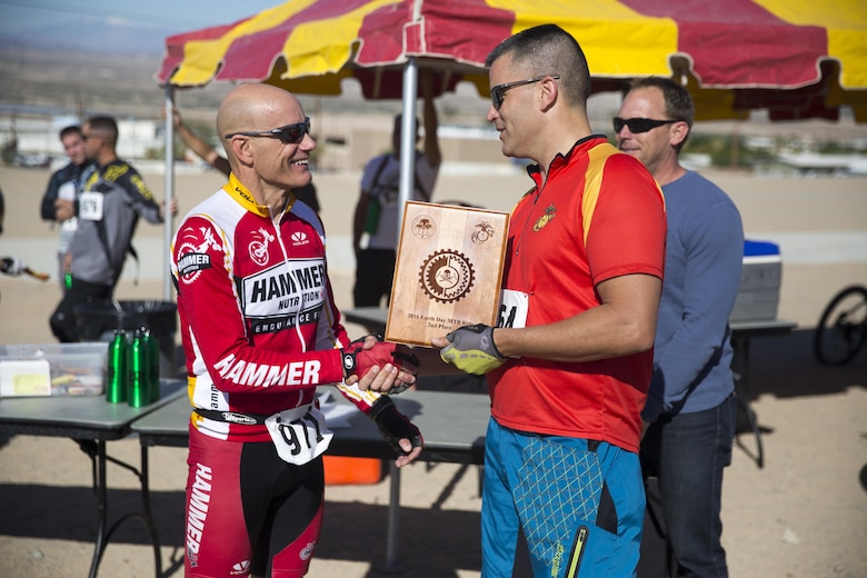 Don Tolbert, systems integration officer, Marine Corps Community-Electronics School, shakes the hand of Lt. Col. Timothy Pochop, director, Natural Resources and Environmental Affairs, after winning second place in the Annual Earth Day Mountain Bike Ride held near Range 100 aboard the Combat Center April 13, 2016. The eight-mile bike ride began and ended at Range 100. (Official Marine Corps photo by Cpl. Julio McGraw/Released)