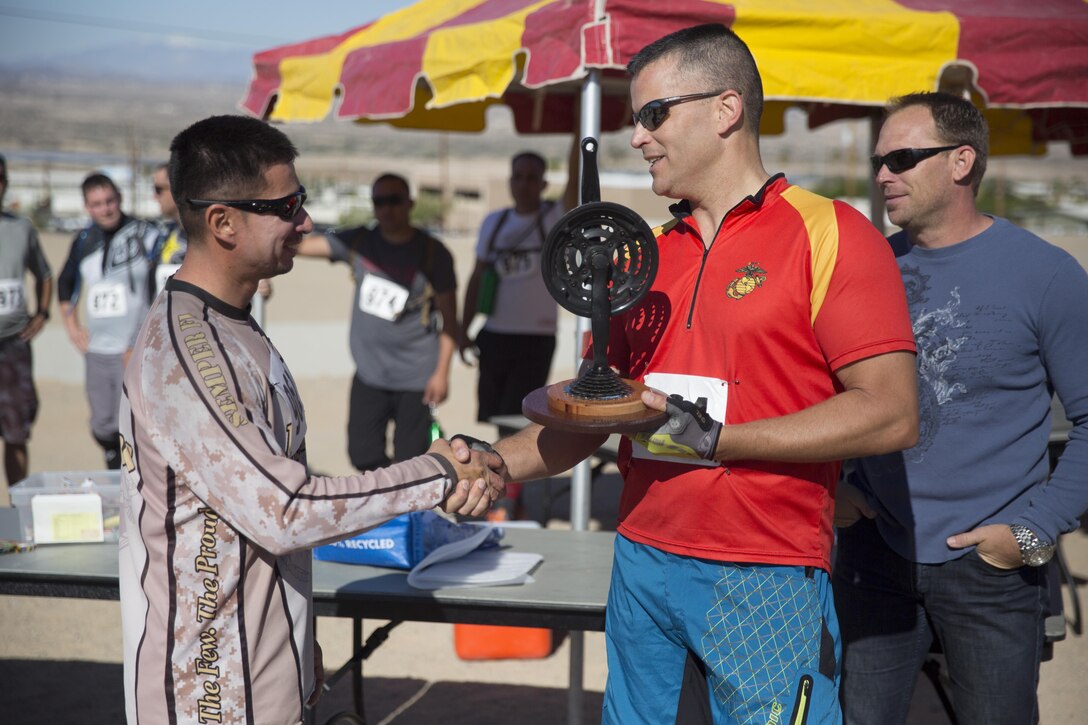 Jesse Santana, tank mechanic, Exercise Support Division, shakes the hand of Lt. Col. Timothy Pochop, director, Natural Resources and Environmental Affairs, after winning first place in the Annual Earth Day Mountain Bike Ride held near Range 100 aboard the Combat Center April 13, 2016. The eight-mile bike ride began and ended at Range 100. (Official Marine Corps photo by Cpl. Julio McGraw/Released)
