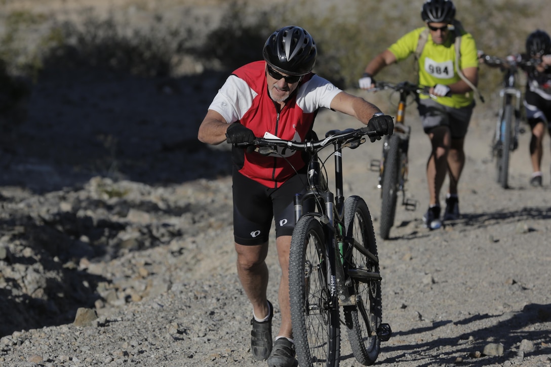 Riders walk their bike up the incline during the Annual Earth Day Mountain Bike Ride held near Range 100 aboard the Combat Center April 13, 2016. The eight-mile ride started at Range 100 and took participants through designated trails behind the range. (Official Marine Corps photo by Pfc. Dave Flores/Released)