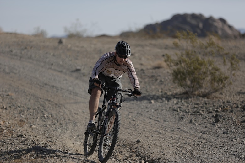 Sam Crabtree, tank mechanic, Exercise Support Division, speeds downhill during the Annual Earth Day Mountain Bike Ride held near Range 100 aboard the Combat Center April 13, 2016. The eight-mile ride started at Range 100 and took participants through designated trails behind the range. (Official Marine Corps photo by Pfc. Dave Flores/Released)
