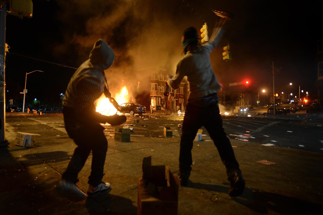 News: Young men throw bottles of beer at burning vehicles as a riot ensues after the funeral of Freddie Gray in Baltimore, April 27, 2015. Gray died April 19 from a severe spinal injury that allegedly occurred while in police custody. Looting and riots broke out in Baltimore after the funeral. The Maryland governor declared a state of emergency. Air Force photo by Staff Sgt. Kenny Holston