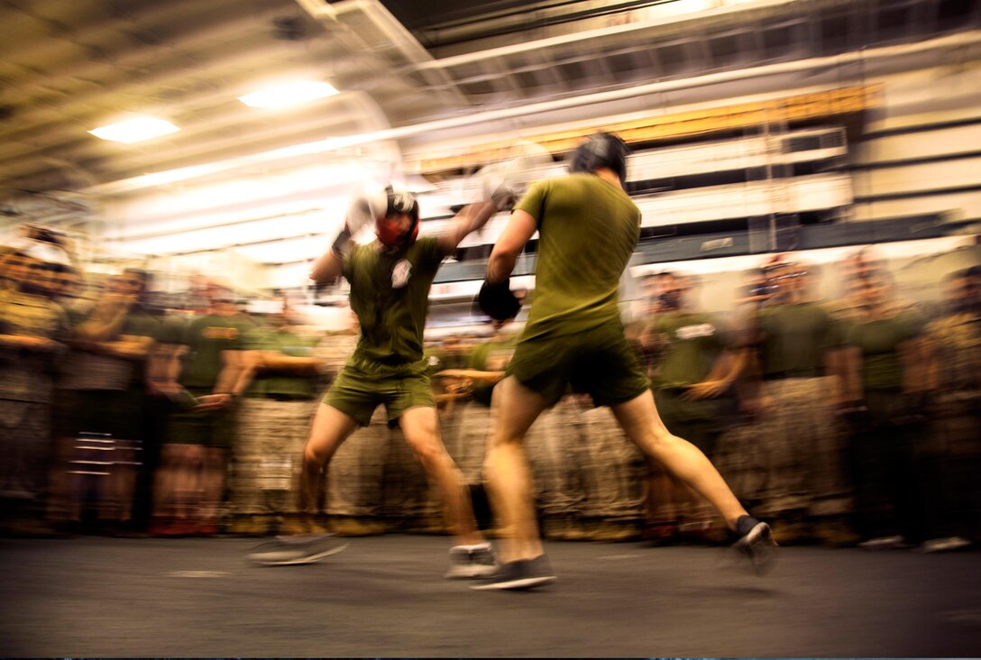 Sports Photography: Marine Corps Cpl. Roman Fernandez, left, and 1st Lt. Paul Hollwedel duke it out in the hangar bay of the USS Essex at sea in the Pacific Ocean, May 29, 2015. Fernandez is a team leader and Hollwedel is the executive officer with Lima Company, Battalion Landing Team 3rd Battalion, 1st Marine Regiment, 15th Marine Expeditionary Unit. The Marines found unique ways to continue to maintain combat readiness during their seven-month deployment through the Pacific and Central Command areas. U.S. Marine Corps photo by Cpl. Elize McKelvey