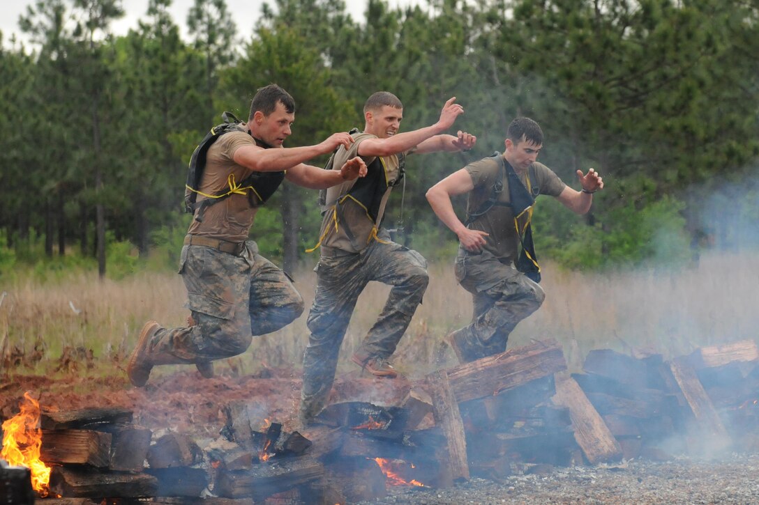 Army 1st Lt. Timothy Nelson, center, Capt. Mark Gaudet, right, and another Army Ranger jump over smoldering logs during the Spartan Race that kicked off Day 2 of the grueling 33rd annual Best Ranger Competition at Fort Benning, Ga., April 16, 2016. The competition is a three-day event consisting physical, mental, and technical challenges in honor of Lt. Gen. David E. Grange Jr. DoD photo by Katie Lange