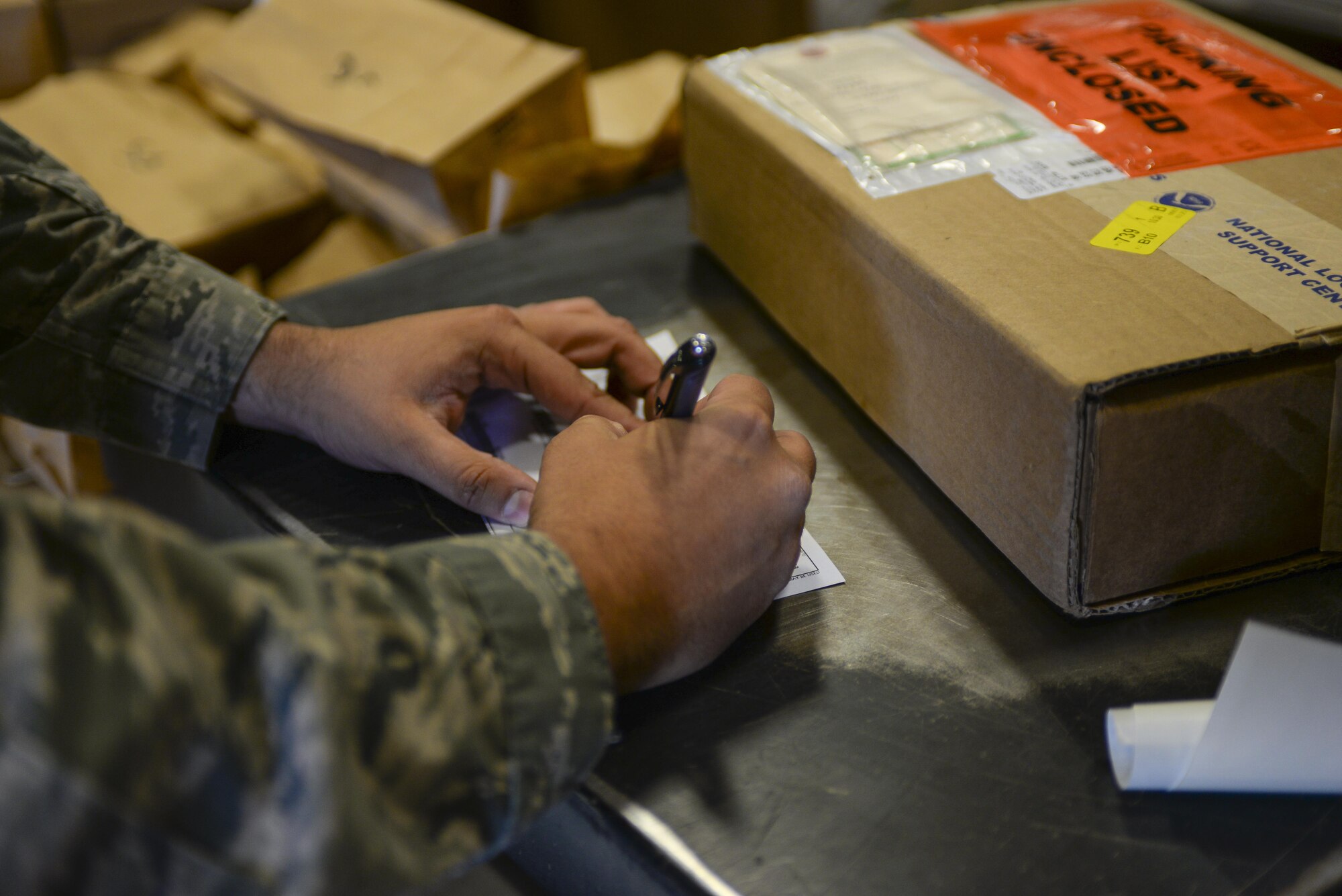Senior Airman Thiago Gandarillas, 99th Logistics Readiness Squadron acting NCO in charge of planning and packaging, fills out a form while preparing a package for shipment at Nellis Air Force Base, Nev., on April 18, 2016. With over 40 percent of traffic management personnel deployed at all times, this team thrived through expert training and cross-utilization of talents to help with mission support, readiness and made significant and lasting contributions to the Nellis AFB, Creech AFB and Nevada Test and Training Range team as well as to the U.S. Air Force Warfare Center mission. (Air Force photo by Airman 1st Class Nathan Byrnes)