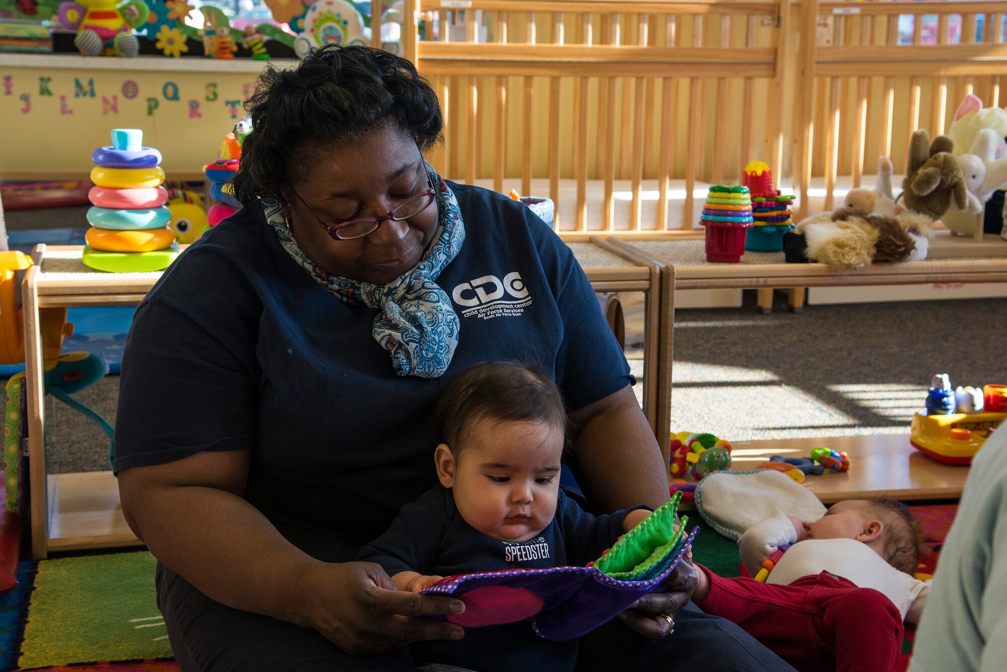 Sandra Rogers, a caretaker at the Child Development Center reads a book to a child April 13, 2016 at Scott Air Force Base. The CDC provides child care for families with children six weeks to five years old, or until the child is ready to begin kindergarten. (U.S. Air Force photo by Airman 1st Class Gwendalyn Smith)