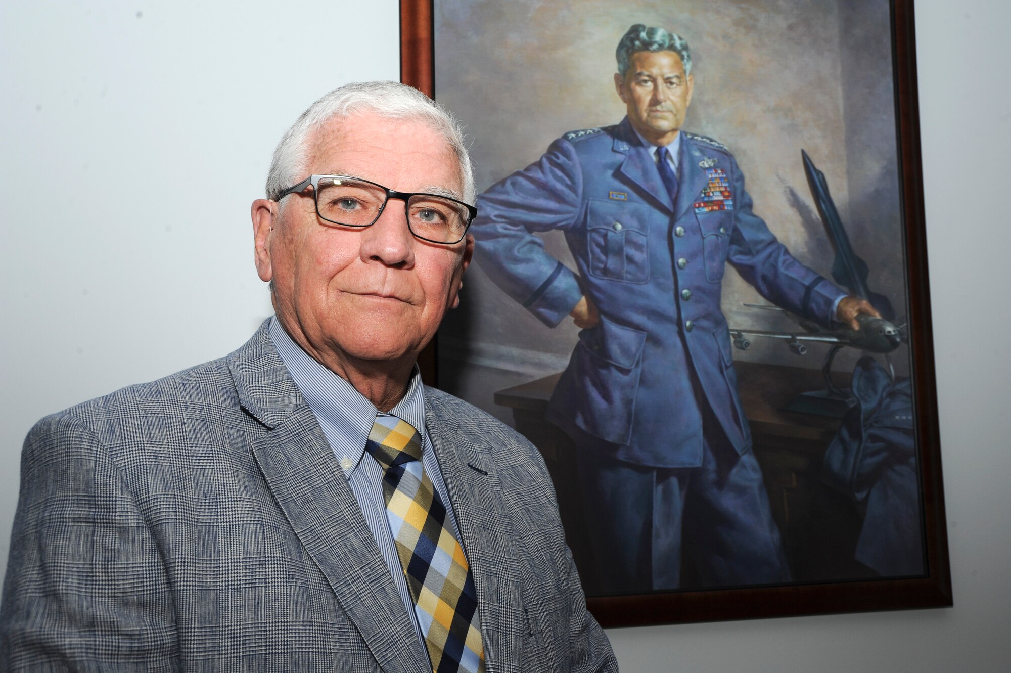 Retired Air Force Lt. Gen. Paul. K. Carlton Jr. poses in front of a portrait of family friend Gen. Curtis LeMay, April 21, 2016, Maxwell Air Force Base, Ala. The former Surgeon General of the Air Force visited Maxwell to share his thoughts with the Air War College Medical Elective students regarding Air Force history and culture. He spoke about what to do when an order is given that doesn’t meet with the Air Force’s moral standards and how to respond. He also gave insight on his friendship with LeMay. Carlton’s father, General Paul K. Carlton Sr. was LeMay’s aid from 1949-1953 and the two families became good friends. Carlton reminisced about fond memories he had with LeMay, such as when he wrote his recommendation letter for the Air Force Academy and gave his children shooting lessons in 1982. Carlton said that he hopes that if anyone remembers anything about LeMay it’s that he was a dedicated warrior. (U.S. Air Force photo/Airman 1st Class Alexa Culbert)