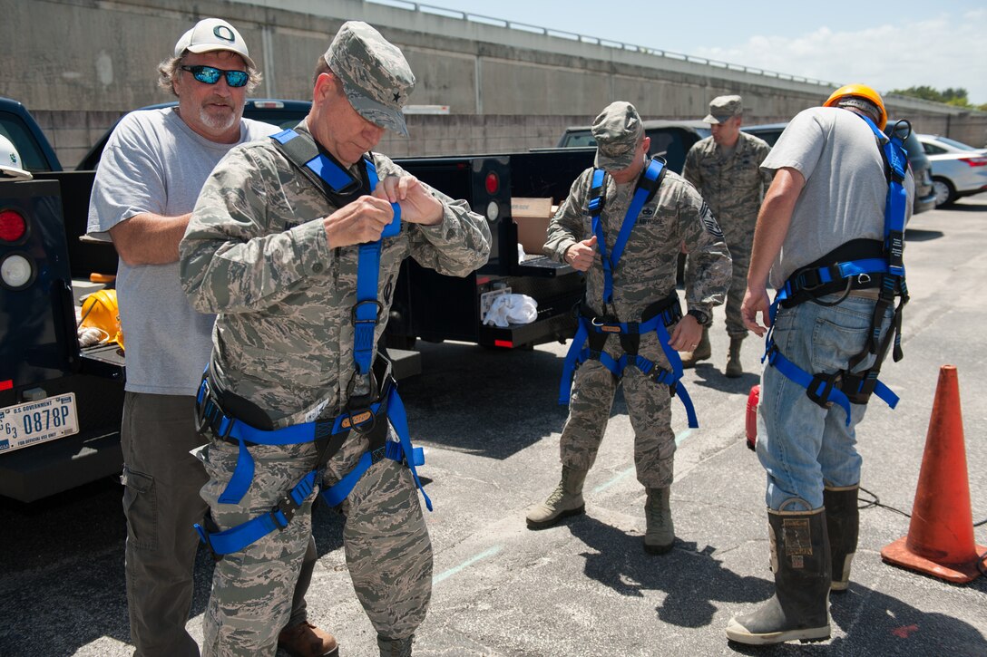 Brig. Gen. Wayne Monteith, 45th Space Wing commander, and Chief Master Sgt. Jason Lamoureux put on safety harnesses before assisting in a repair and replacement of a copper communication line seeding a Florida Power and Light power station in Manhole 208 April 18, 2016, at Patrick Air Force Base, Florida. The wing commander and command chief visit with 45th SW members each month in order to gain a better understanding of the jobs their Airmen do daily, address their questions and concerns and look for ways they can provide additional support. (U.S. Air Force photo by Benjamin Thacker/released)