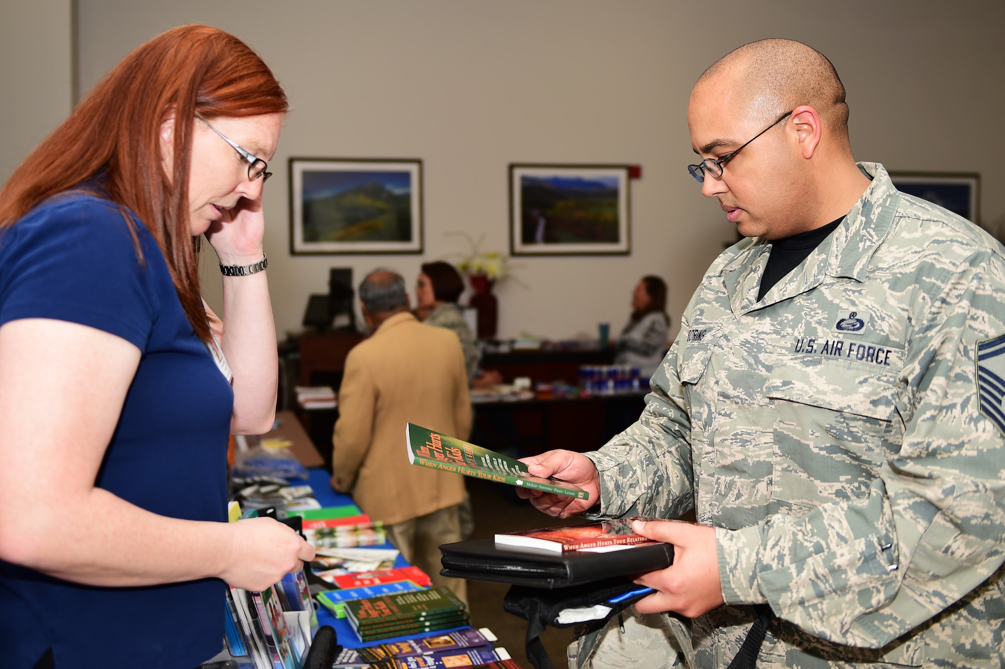 Senior Master Sgt. Crumel Mooring, 460th Space Wing Equal Opportunity superintendent, receives books from Christine Baird, 460th Medical Group family advocacy nurse, during a Child Abuse Awareness Month information fair April 15, 2016, on Buckley Air Force Base, Colo. All children deserve to grow up in a caring and loving environment, yet in the United States, hundreds of thousands of children are neglected or abused each year, often causing lasting consequences with between four and eight children dying every day from abuse or neglect. (U.S. Air Force photo by Senior Airman Racheal E. Watson/Released) 