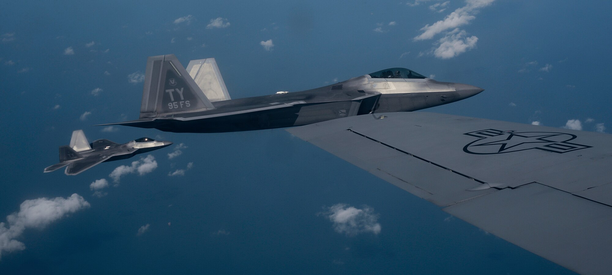 Two U.S. Air Force 95th Fighter Squadron F-22 Raptors from Tyndall Air Force Base, Fla., fly alongside a 100th Air Refueling Wing KC-135 Stratotanker assigned to RAF Mildenhall, England, April 19, 2016, over the Norfolk Sea. The fifth generation, multi-role fighter aircraft participated to maximize training opportunities, affirm enduring commitments to NATO allies, and deter any actions that destabilize regional security. (U.S. Air Force photo by Senior Airman Victoria H. Taylor/Released)