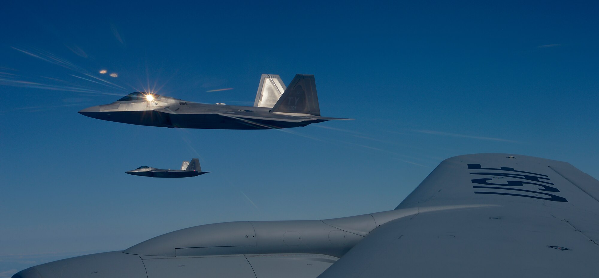 Two U.S. Air Force 95th Fighter Squadron F-22 Raptors from Tyndall Air Force Base, Fla., fly alongside a 100th Air Refueling Wing KC-135 Stratotanker assigned to RAF Mildenhall, England, April 19, 2016, over the Norfolk Sea. The fifth generation, multi-role fighter aircraft participated to maximize training opportunities, affirm enduring commitments to NATO allies, and deter any actions that destabilize regional security. (U.S. Air Force photo by Senior Airman Victoria H. Taylor/Released)