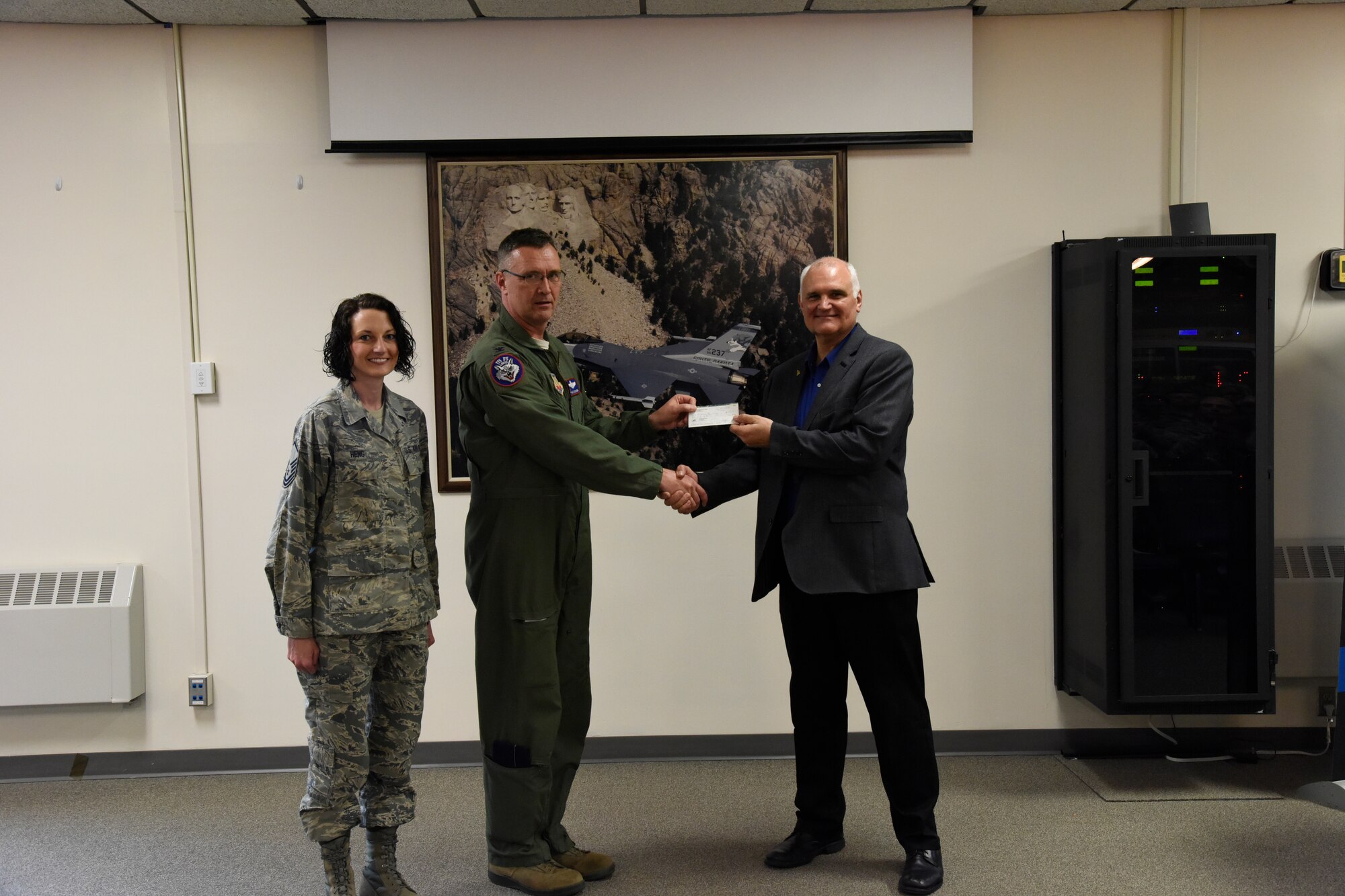 SIOUX FALLS, S.D. - Master Sgt. Trish Heng, holiday party committee member, and Col. Nate Alholinna, 114th Fighter Wing vice commander, present Rick Weber, Children's Home Society of South Dakota development director, with a $500 donation from unit members which was collected at the holiday party in Dec. 2015. (U.S. Air National Guard photo by Senior Master Sgt. Nancy Ausland/Released)