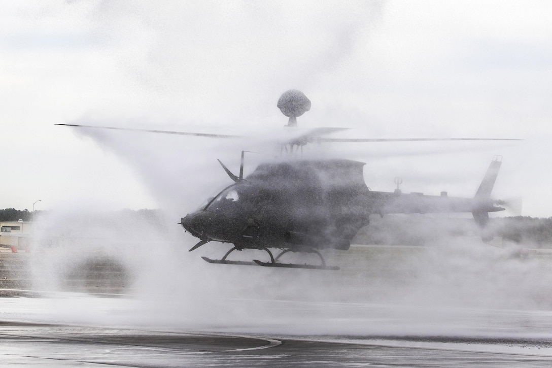 An OH-58 Kiowa Warrior is showered by an arch of water from firetrucks following their final formation flight at Simmons Army Airfield, N.C., April 15, 2016. The crew and helicopter are assigned to the 82nd Airborne Division’s 17th Cavalry Regiment, 82nd Combat Aviation Brigade. The water is symbolic to the retirement of the aircraft, which has been in the unit's inventory since the summer of 1990. Army photo by Staff Sgt. Christopher Freeman