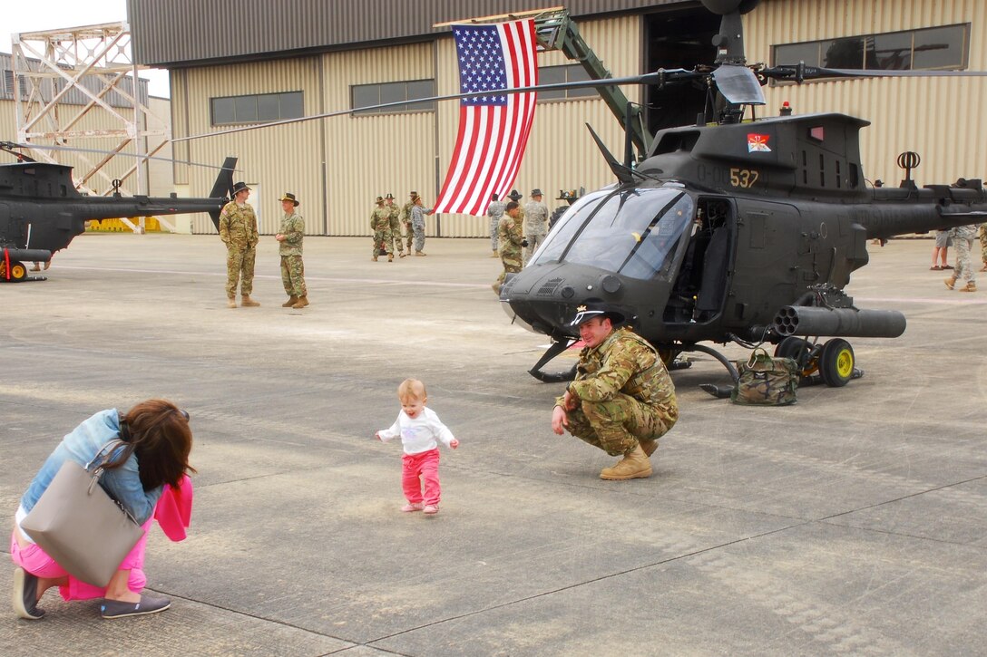 A soldier is greeted by his family after completing a final flyover "salute" formation at Simmons Army Airfield, N.C. April 15, 2016. Army photo by Sgt. Neil A. Stanfield