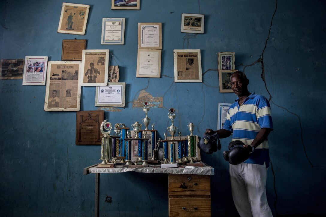 Portrait Personality: A boxing coach poses with championship awards won by students from his program at a school during Operation Continuing Promise in Santo Domingo, Dominican Republic, Aug. 21, 2015. Operation Continuing Promise is a mission to countries in Central and South America and the Caribbean, where the U.S. military and its partnering nations work with host nations and a variety of governmental and non-governmental agencies in civil-military operations. Marine Corps photo by Sgt. James R. Skelton