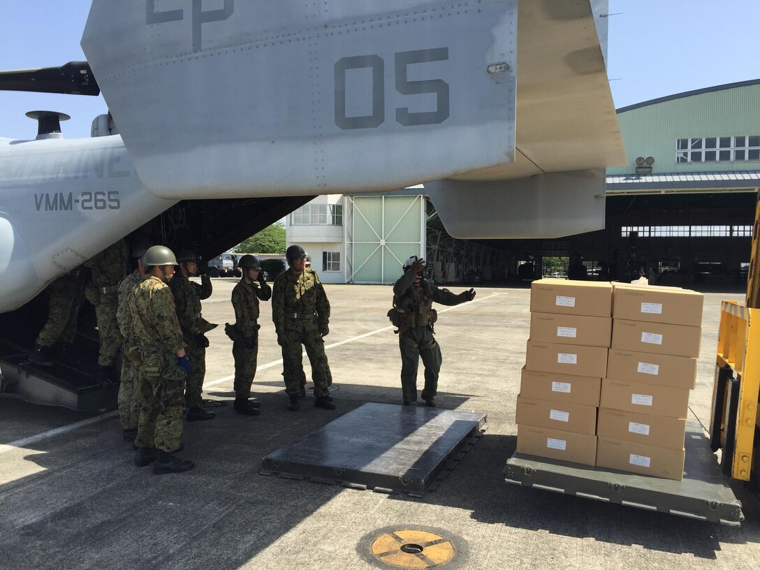 A U.S. Marine guides a forklift as Japanese soldiers prepare to load relief supplies into a U.S. Marine Corps MV-22B Osprey aircraft at the Kumamoto airport in Japan, April 22, 2016. Marine Corps photo by Capt. Jennifer Giles