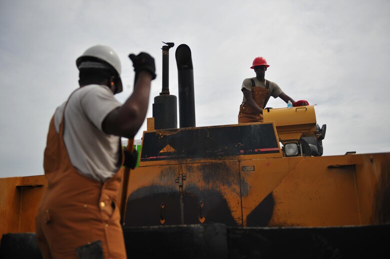 Staff Sgt. Roy Ingram, a heavy equipment operator with the 567th RED HORSE squadron, Seymour Johnson Air Force Base, N.C., right, opens the paving machine’s hopper while Senior Airman Yuri Howell, a heavy equipment operator with the 567th RED HORSE squadron, scrapes out the inside before adding more asphalt at Hurlburt Field, Fla., April 20, 2016. The two-week milling and paving course repaired a parking lot and also served as a training opportunity. (U.S. Air Force photo by Airman 1st Class Joseph Pick)