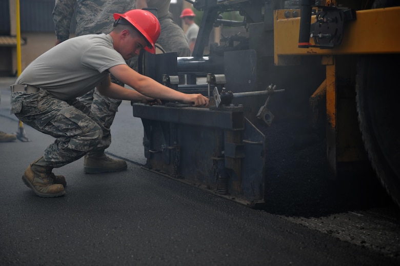 Airman Keean Paltz, a heavy equipment operator with the 823rd RED HORSE squadron, turns the end gate of a paving machine to regulate the flow of asphalt onto a parking lot at Hurlburt Field, Fla., April 20, 2016. As part of a two-week milling and paving training course, Airmen from across the globe laid more than 250 tons of asphalt to repair a parking lot. (U.S. Air Force photo by Airman 1st Class Joseph Pick)