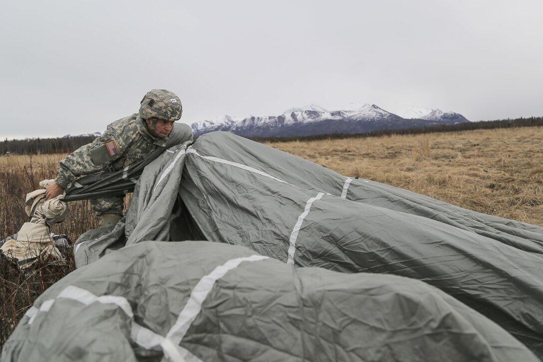Army Sgt. Melissa Perez recovers her parachute during a practice forced-entry parachute assault on Malemute drop zone at Joint Base Elmendorf-Richardson, Alaska, April 5, 2016. Perez is assigned to the 25th Infantry Division, 4th Brigade Combat Team (Airborne). Air Force photo by Alejandro Pena