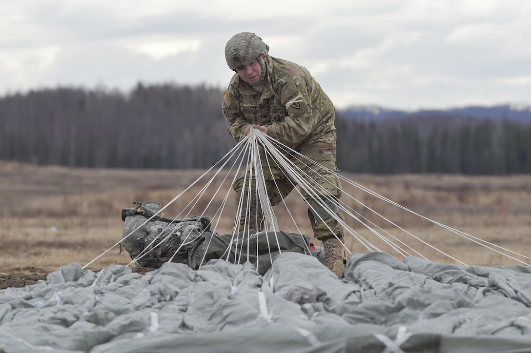 Army Spc. Pete Disston recovers his gear during a practice forced-entry parachute assault on Malemute drop zone at Joint Base Elmendorf-Richardson, Alaska, April 5, 2016. Disston is assigned to the 25th Infantry Division, 4th Brigade Combat Team (Airborne), Alaska. Air Force photo by Alejandro Pena