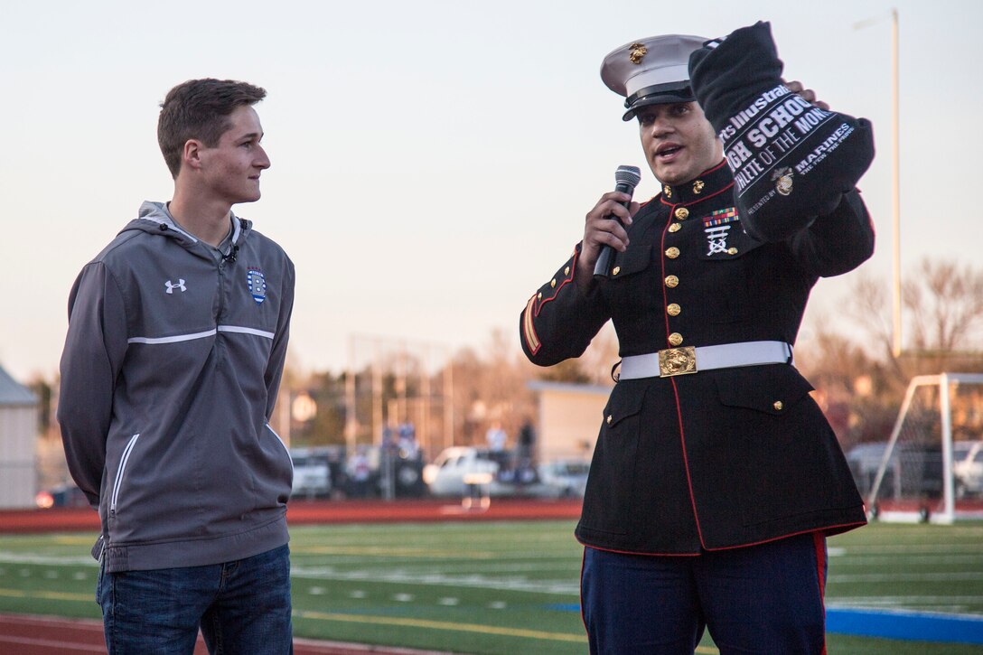 Staff Sgt. David Hall, a recuiter with Recruiting Station Denver, motivates the crowd at a high school soccer game while standing next to Porter Milner, a Broomfield High School athlete and senior, during the Sports Illustrated Athlete of the Month presentation at Broomfield High School, April 21, 2016. Milner received the award not just for his athletic skills, but also his dedication to leadership, camaraderie and personal development.