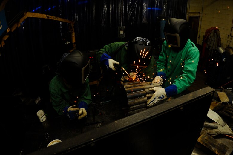 Staff Sgt. Corina Waxenfelter, 22nd Civil Engineer Squadron structures craftsman, welds the base of a sculpture with the help of Airman 1st Class Adrian Holland, 22nd CES structures journeyman, left, and 2nd Lt. Ramoane Jordan, 22nd CES deputy chief of project management, April 20, 2016, at McConnell Air Force Base, Kan. During the 2016 Welding Competition each squadron had five hours to create a sculpture based on the 60th Anniversary KC-135 Stratotanker theme. (U.S. Air Force photo/Airman Jenna K. Caldwell)   