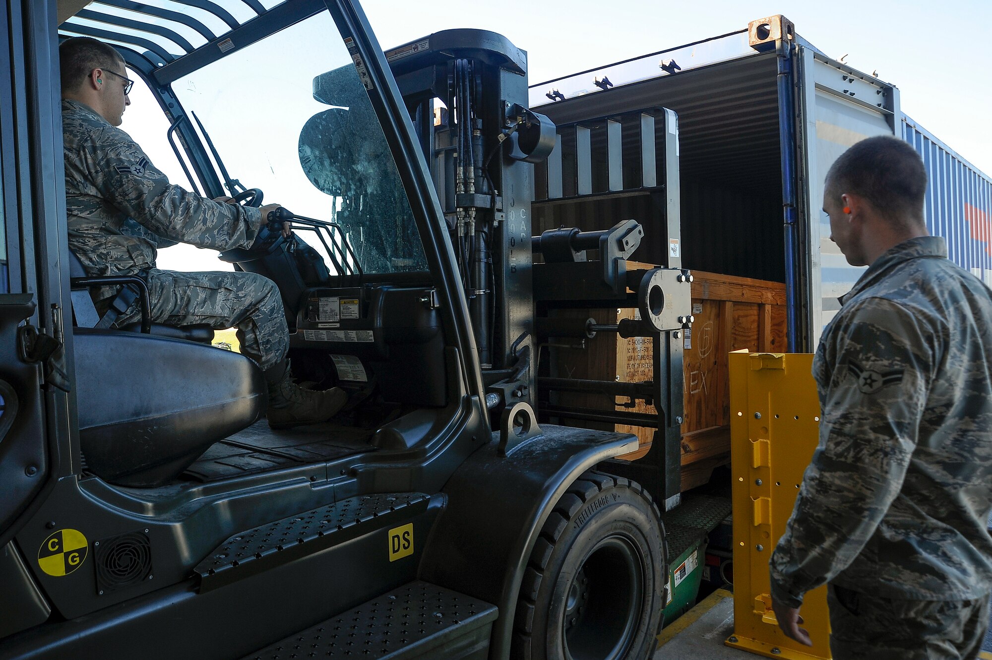 Airman 1st Class Wyatt Simmons, left, a traffic management apprentice with the 6th Logistics Readiness Squadron (LRS) loads a crate into a container as Airman 1st Class William West, a traffic management journeyman with the 6th LRS, right, spots him for safety at MacDill Air Force Base, Fla., April 21, 2016. Once a crate has been loaded, it will be shipped overseas. (U.S. Air Force photo by Airman 1st Class Mariette Adams)
