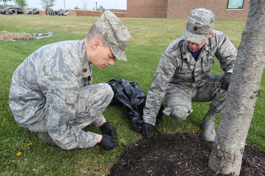 Maj. Michael Hopkins (left), Air Force Legal Operations Agency Special Victims Counsel Program deputy division chief, and Maj. Kurt Mabis (right), AFLOA Civil Law and Litigation directorate executive, pick weeds around the Jones building at Joint Base Andrews, Md., April 22, 2016. Team Andrews cleaned up around base in commemoration of Earth Day. (U.S. Air Force photo by Senior Airman Joshua R. M. Dewberry/RELEASED)
