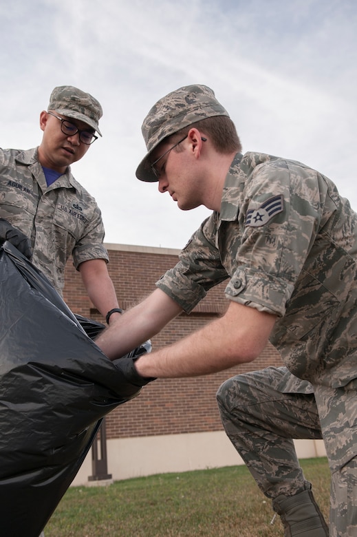 Tech. Sgt. James Aguilar, 11th Comptroller Squadron customer service technician and Senior Airman Josh Ulrich, 11th CPTS payroll technician, work together to dispose of litter at Joint Base Andrews, Md., April 22, 2016. The Airmen assisted with the base-wide clean up in commemoration of Earth Day. (U.S. Air Force photo by Airman Gabrielle Spalding/Released)