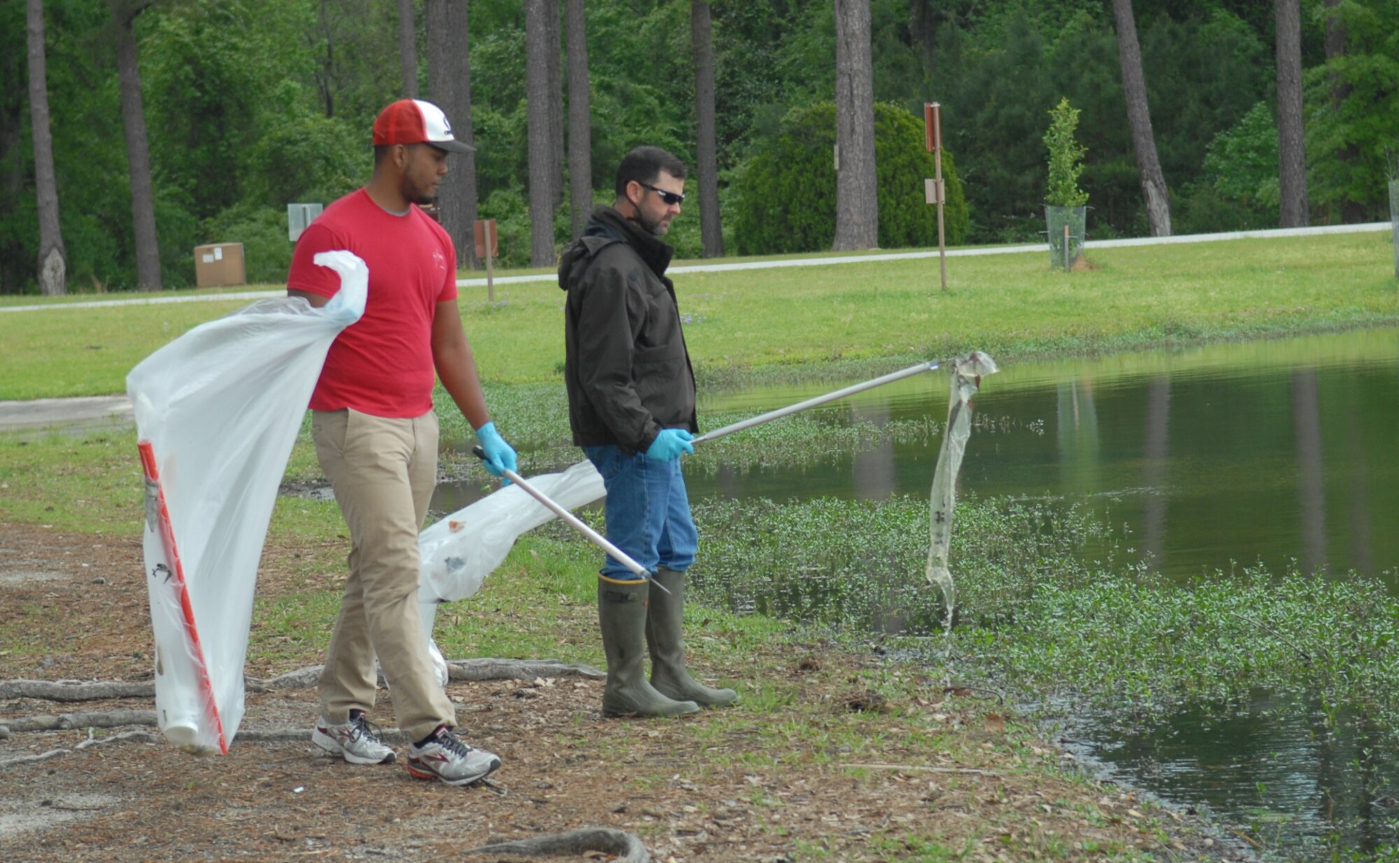 Jacob Tuttle, Natural Cultural Resource manager right) and Darquelle Gooch, Georgia Southern University Biology pre-medical student, clean-up the bank of Scout Lake, April 15, 2016. (U.S. Air Force photo by Misuzu Allen)
