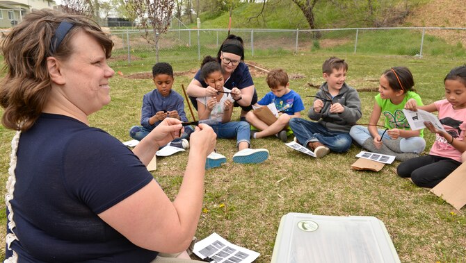 Annie Kitterman, Hill Air Force Base cultural resource manager, shows children from the base’s youth center how to craft pipe-cleaner horses April 22. The horses replicated split twig figures originally made by members of a hunting and gathering culture during what archaeologists call the Late Archaic period, 2,000 to 4,000 years ago. The crafting event took place in conjunction with Earth Day in the base’s housing area where earlier the children planted a tree. (U.S. Air Force photo by Paul Holcomb)