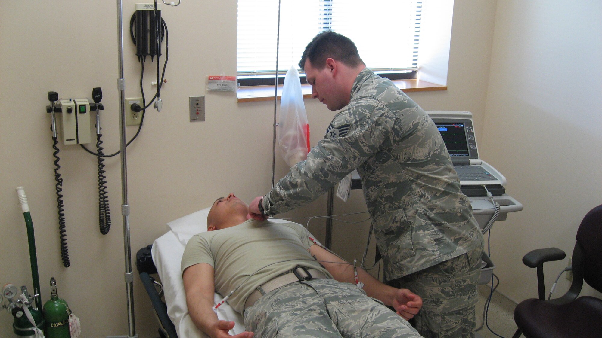 Senior Airman Thomas Hartless, a Flight and Operational Medicine Technician with the 88th Aerospace Operational Medicine Squadron demonstrates the use of the EKG machine on Senior Airman Omar Herrera, a Public Health Technician.  (U.S. Air Force photo/Kimberly Gaither) 
