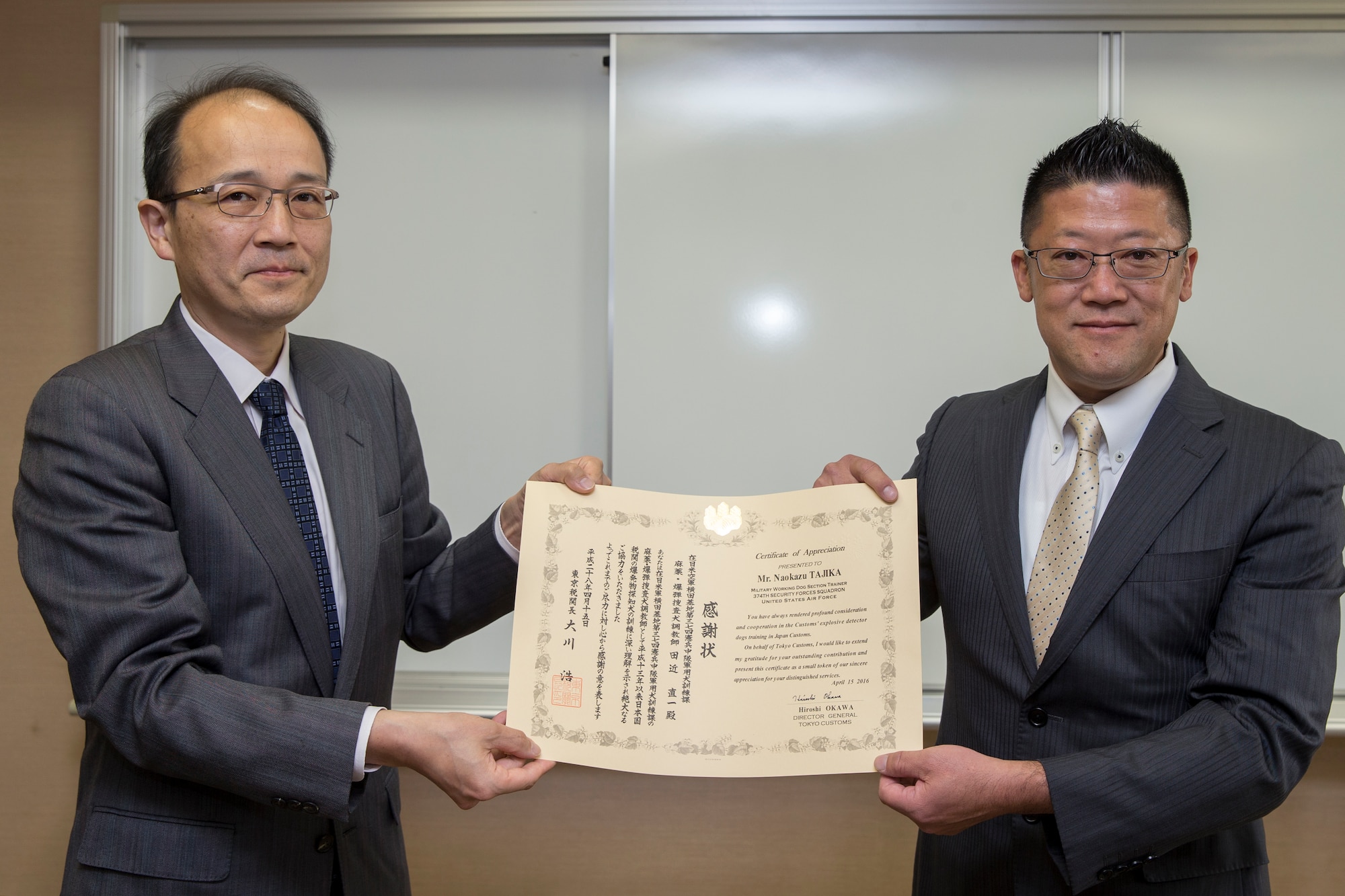 (Left to right) Tomohiro Matsushige, Tokyo Customs Director of Coordination Division deputy director general, presents a letter of appreciation to Naokazu Tajika, 374th Security Forces Squadron military working dog trainer, at Tokyo Customs Canine Training Center, Chiba prefecture, Japan, April 15, 2016. Tajika has been a dog handler for the 374 SFS for over 20 years. (U.S. Air Force photo by Yasuo Osakabe/Released) 