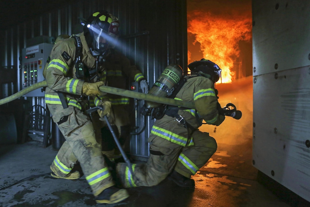 Air Force fire protection specialists enter a room while conducting firefighting drills in the live-fire simulator at Joint Base Elmendorf-Richardson, Alaska, April 13, 2016. The firefighters are assigned to the 673rd Civil Engineer Squadron. Air Force photo by Alejandro Pena