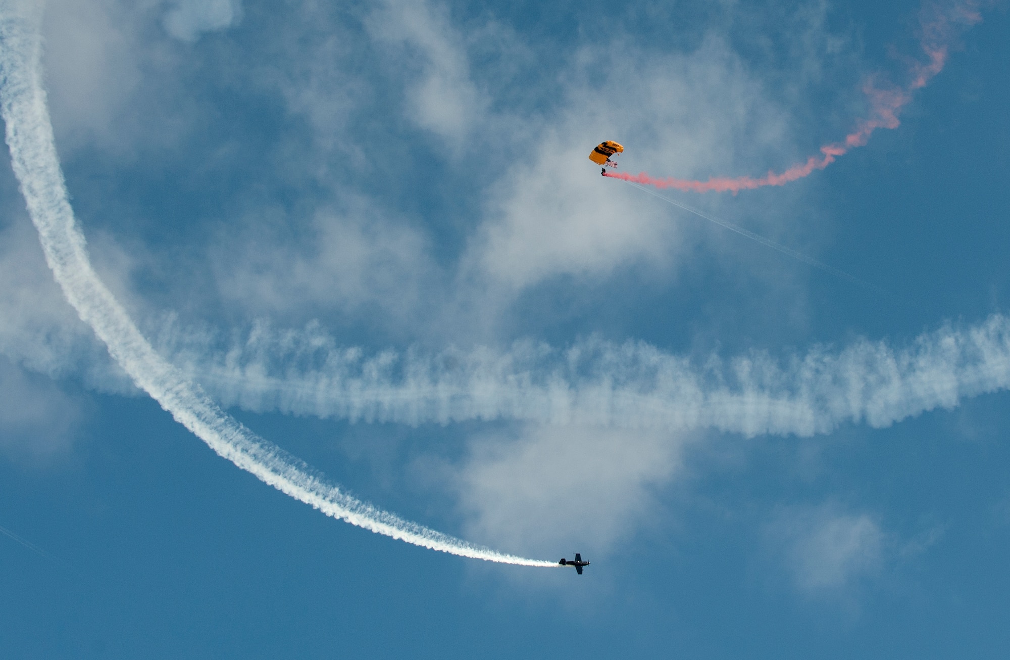 A member of the U.S. Army Golden Knights parachute team performs a flag jump while being circled by an MXS-RH Aerobatic Aircraft during the AirPower over Hampton Roads Open House at Langley Air Force Base, Va., April 23, 2016. The Open House is free, open to the public and showcases modern and historical military aircraft and civilian performers. (U.S. Air Force photo by Airman 1st Class Kaylee Dubois)