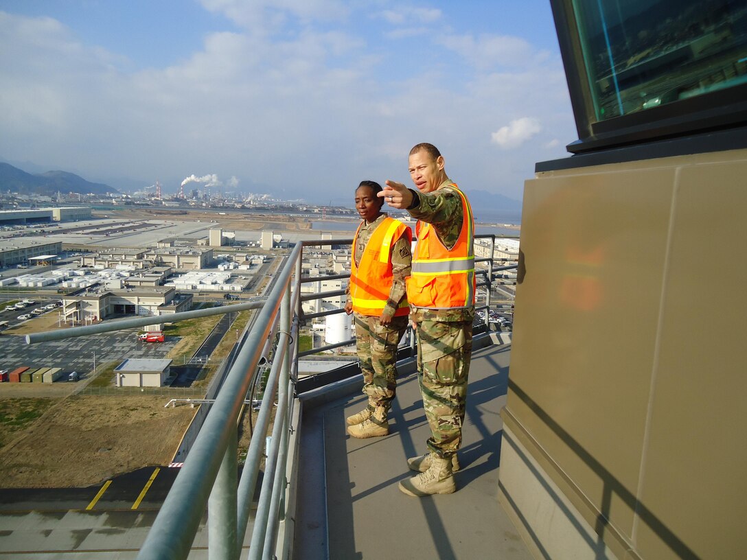 Capt. ChaTom Warren, civil engineer, Iwakuni Resident Office, U.S. Army Corps of Engineers, Japan District shows Command Sgt. Major Yolanda Tate a view of Marine Corps Air Station Iwakuni from the tallest building on base, the Air Traffic Control Tower. 