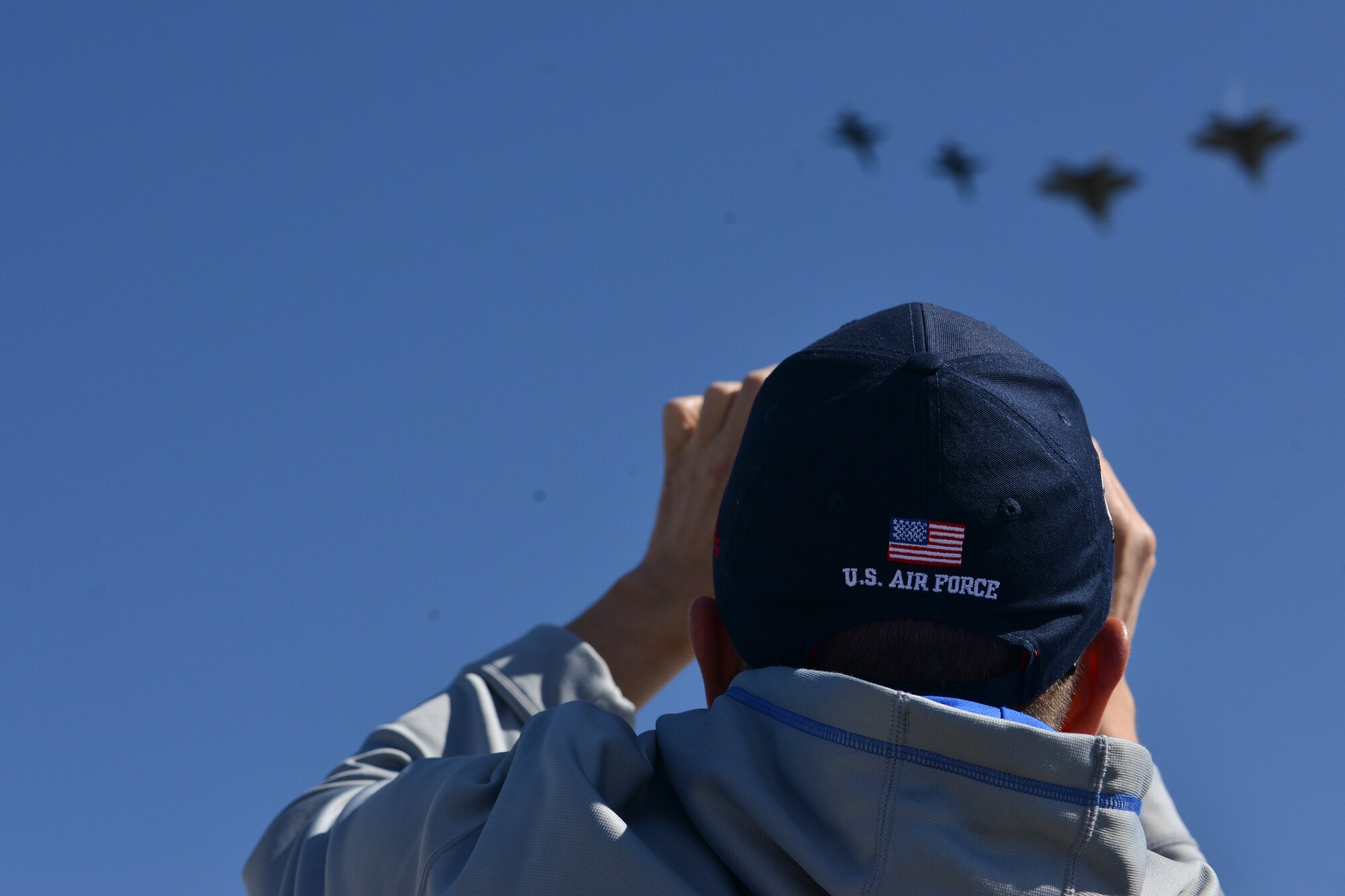 An AirPower over Hampton Roads Open House spectator photographs a fly-by at Langley Air Force Base, Va., April 24, 2016. The fly-by consisted of U.S. Air Force F-22 Raptors and T-38 Talons. (U.S. Air Force photo by Staff Sgt. Natasha Stannard)