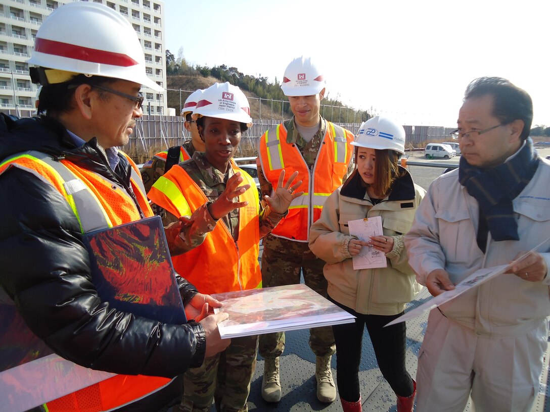 Keita Tanaka, project manager, Iwakuni Resident Office, U.S. Army Corps of Engineers, Japan District holds a map of the Atago site where a housing area, sports complex and bridge are being built on Marine Corps Air Station Iwakuni, as Command Sgt. Major Yolanda Tate speaks about the magnitude of the project. 