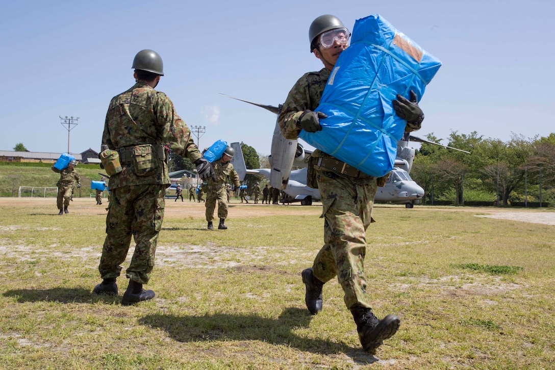 Japanese soldiers carry supplies from a U.S. Marine Corps MV-22B Osprey aircraft at the Hakusui Sports Park, Kyushu Island, Japan, April 22, 2016. Marine Corps photo by Cpl. Darien J. Bjorndal