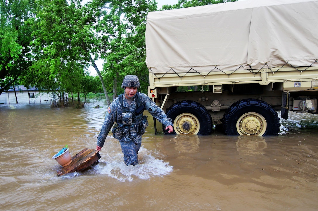 A soldier pulls a wooden table and plant pot through deep water while helping stranded residents with their belongings during severe flooding in Wharton, Texas, April 21, 2016. Texas Army National Guard photo by 1st Lt. Zachary West