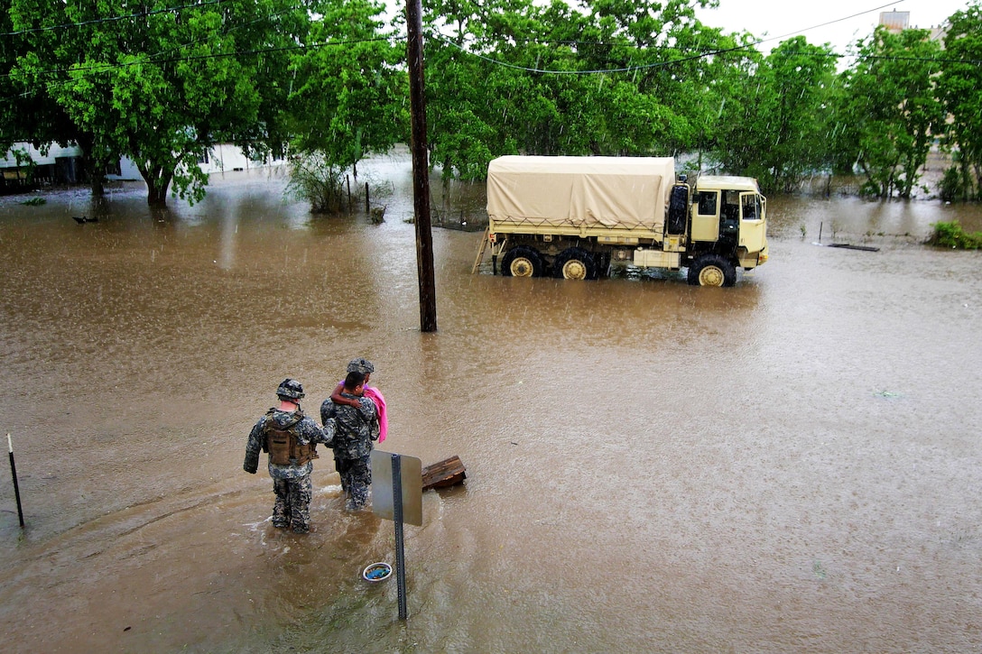 Soldiers carry a young girl through deep water to load her onto a light multi-terrain vehicle during severe flooding in Wharton, Texas, April 21, 2016. Texas Army National Guard photo by 1st Lt. Zachary West 