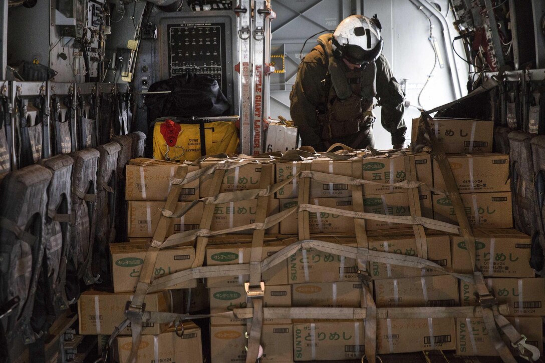 A Marine crew chief secures cargo straps around a large pile of supplies inside a U.S. Marine Corps MV-22B Osprey aircraft aboard the JS Hyuga at sea, near Kumamoto, Japan, April 23, 2016. Marine Corps photo by Cpl. Nicole Zurbrugg