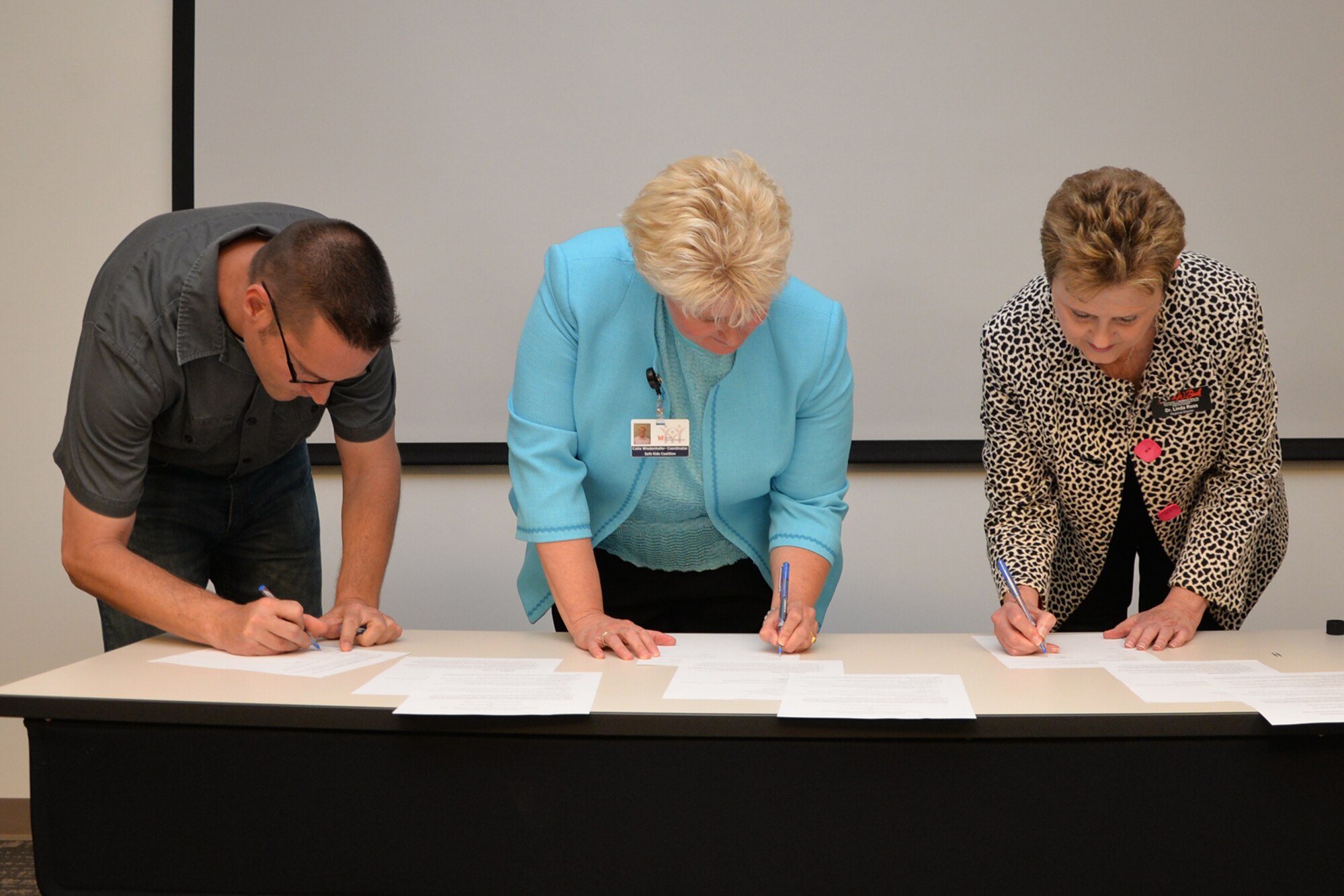 Neil Townley, 17th Training Wing Safety chief; Catie G. Wiedenhofer, Safe Kids San Angelo coordinator; and Dr. Linda C. Ross, Laura W. Bush Institute for Women’s Health director, sign Memorandums of Understanding at the Devon Energy office in San Angelo, Texas, April 20, 2016.  The purpose of the Safety Risk Reduction Programs for All Ages MOU is to set the conditions governing the training of personnel and families from Goodfellow and Tom Green County. (U.S. Air Force photo by Airman 1st Class Randall A.S. Moose/Released)